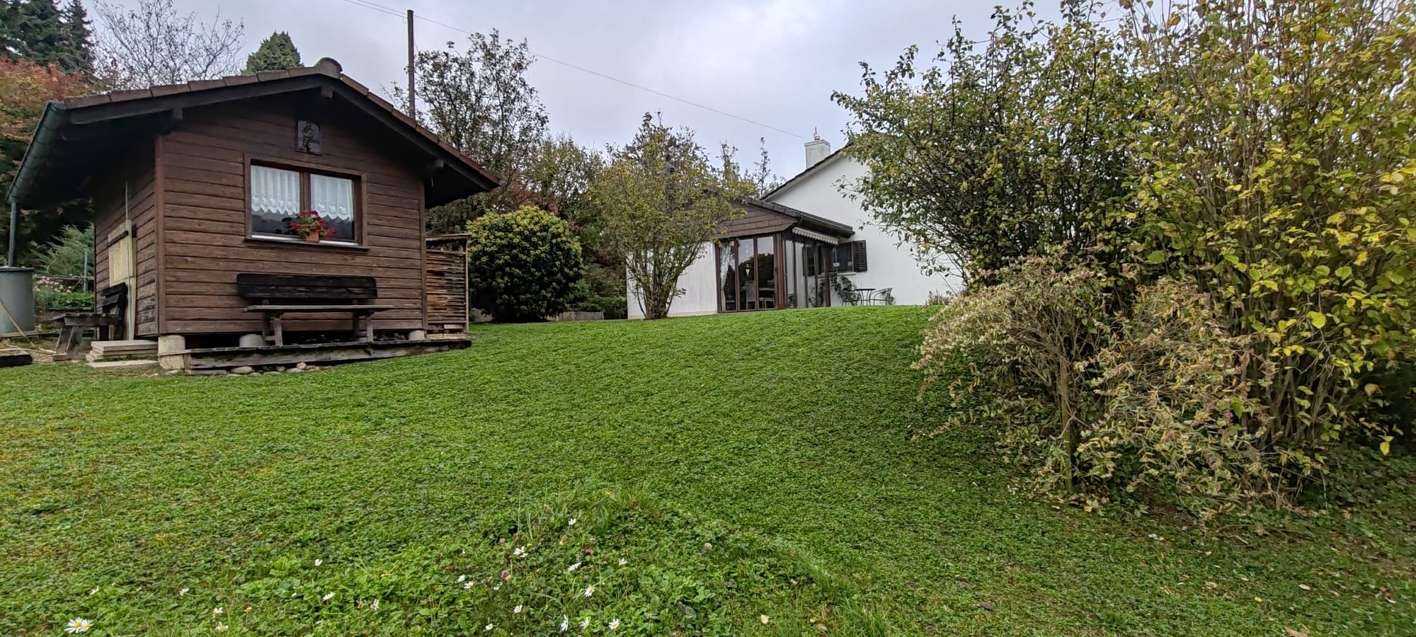 Garten mit gepflegtem Rasen und Holzhütte
